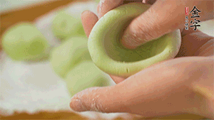 將均分的艾草面團搓成圓，挖一個窩，放入餡心，再搓成圓。