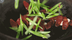 先后下香腸片、四季豆絲均勻翻炒，加適量清水燜煮一下。