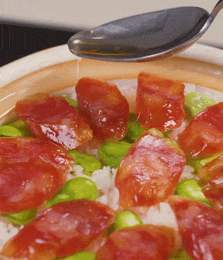 大米出現(xiàn)小孔時開蓋放香腸，往鍋邊淋入少許油，再燜煮8~10分鐘左右。