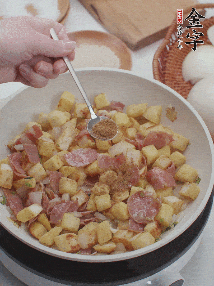 起鍋少油，煸香洋蔥丁、蔥白，加入金字培根火腿翻炒幾下，再加入饅頭丁、1小勺孜然粉、少許鹽翻炒均勻并鋪平。