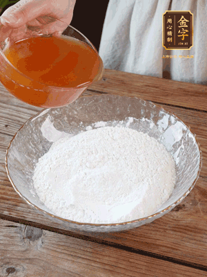 轉(zhuǎn)化糖漿、枧水、花生油攪拌均勻，加入面粉混合，醒發(fā)2小時(shí)。捏成23g一個(gè)的小球