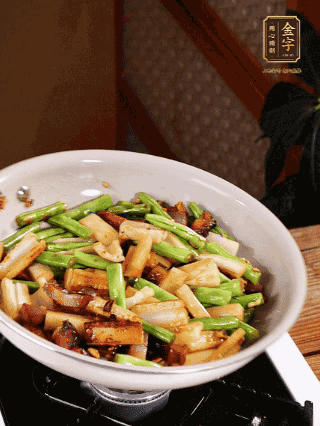 油熱下蒜末、干辣椒、醬肉煸炒出香味，依次下藕條、豆角翻炒均勻